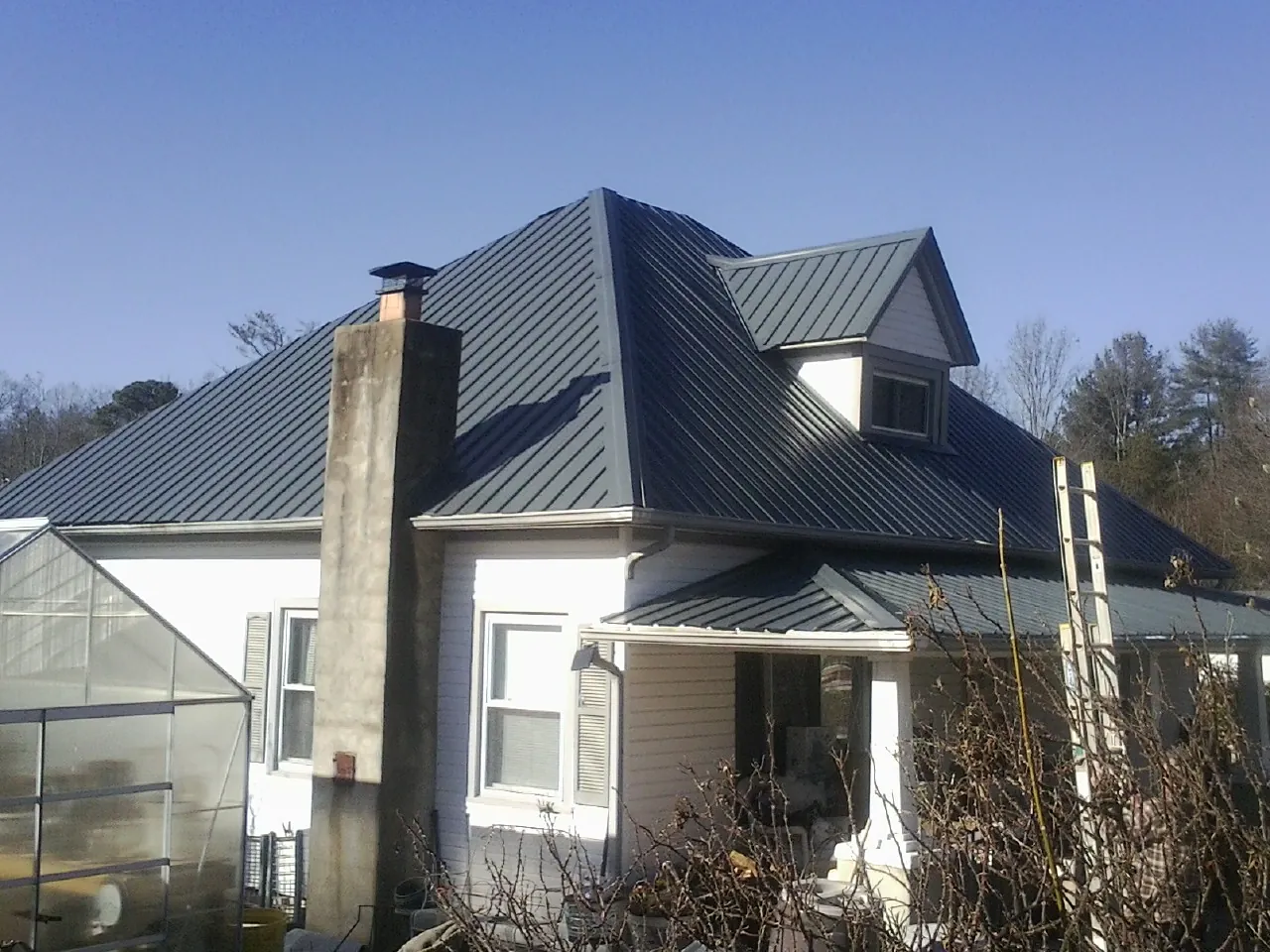 Dark blue standing seam metal roof on a white farmhouse with dormer — Slate & Tile Roof Repair by Roofing Brothers in Marengo