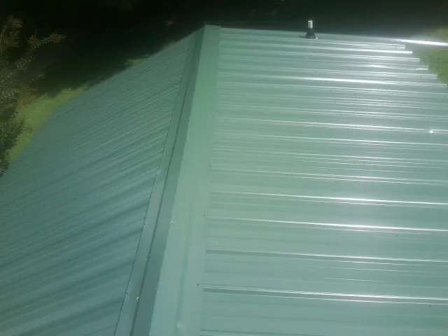 New green metal panels meeting at the ridge of a roof — Flat Roof Repair work by our crew in Marengo