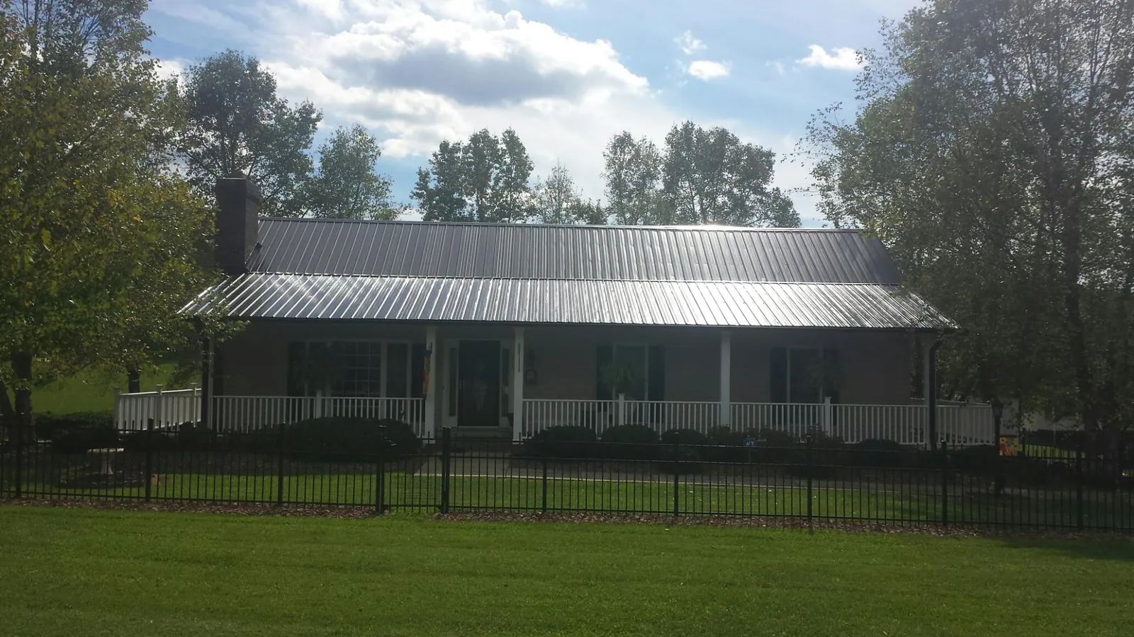 Gray metal roof on a brick ranch with a full width front porch — Gutter Guard Installation work by our crew in Marengo